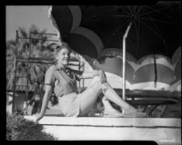 Mona Ohrtland seated beneath a sun umbrella, Palm Springs, 1940