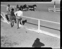 Three spectators watch a harness race at the Palm Springs Field Club, 1937