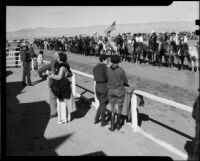 Spectators watch a row of equestrians on the track at the Palm Springs Field Club, 1937