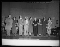 Cast members of a play standing in a row on stage, circa 1940-1965