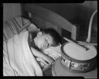 Boy asleep in bed next to a toy drum at the Children's Home Society, Los Angeles, 1935-1960