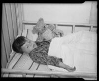 Boy asleep in bed holding a teddy bear at the Children's Home Society, Los Angeles, 1935-1960