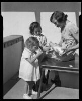 Girl pouring glasses of milk for smaller girls at the Children's Home Society, Los Angeles, 1935-1960