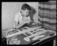 Boy constructing a model airplane following a plan at the Children's Home Society, Los Angeles, 1935-1960