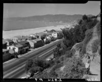 Bird's-eye view of woman on cliff overlooking beach houses along Santa Monica Beach, 1947 to 1952