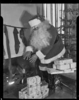 Santa Claus next to presents and Christmas tree at Adelbert Bartlett's house, Santa Monica, 1938