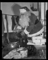 Santa Claus next to presents and Christmas tree at Adelbert Bartlett's house, Santa Monica, 1938