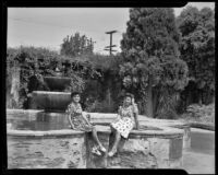 Two women seated at the fountain of the Mission San Fernando Rey de España, Los Angeles, circa 1946?
