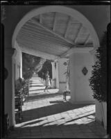 Model Mona Ohrtland carrying a croquet mallet on a walkway at La Quinta Hotel, Indio, circa 1940