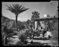 Desert house and garden with a man seated at a well, Palm Springs, 1935