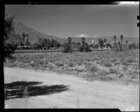 View across open land towards a house and the bell tower of the El Mirador Hotel, Palm Springs, 1935