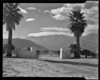 Horseback rider passing a gated drive on a dirt road, Palm Springs, 1941
