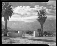 Horseback riders passing a gated drive on a dirt road, Palm Springs, 1941