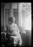 Elderly woman seated in front of an open window, 1937