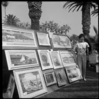 Artist standing next to her paintings at a Santa Monica Art Association exhibition at Palisades Park, Santa Monica, circa 1965