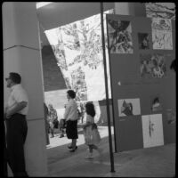 People attending an art exhibition in the courtyard of Perloff Hall at UCLA, Los Angles, circa 1960