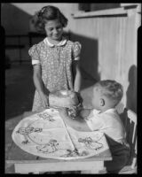 Girl serving a birthday cake to a toddler at the Children's Home Society, Los Angeles, 1935-1960
