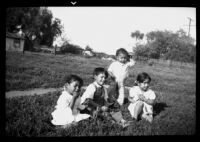 Four children in an open field with houses in the background, 1938