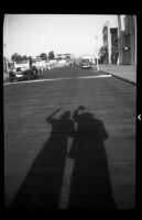Shadows of 2 women on a commercial street, 1938