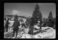 Sled dogs, men, cars, and toboggan in snow, recovery operation, June Lake, 1938