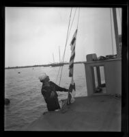 Sea Scout Bill Boyd aboard Pinta with signal flags, Balboa (Newport Beach), 1937