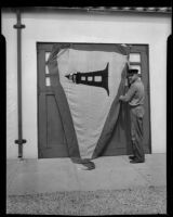 Point Vicente Lighthouse keeper Anton Trittinger with flag awarded for efficiency, Rancho Palos Verdes, 1935