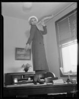 Fan dancer Joyce Baker posing standing on desk, 1935
