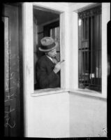 Los Angeles police sergeant Howard L. Barlow dusting window frame for fingerprints, Los Angeles, 1927