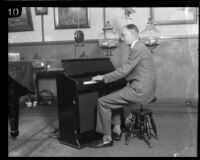 E. K. Barnes, manager of KHJ radio station, plays a piano, Los Angeles, circa 1925