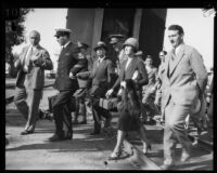 Commander Richard Byrd, Mrs. Marie A. Byrd and their traveling companions walk through the railroad yard, Los Angeles, 1928