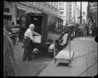 Man unloading a box from an armored car on commercial street after the Long Beach earthquake, Southern California, 1933
