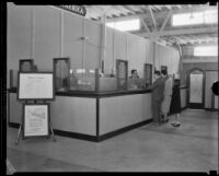 Family at a temporary branch of the Bank of America in the Oil Equipment and Engineering Exposition hall after the Long Beach earthquake, Compton, 1933