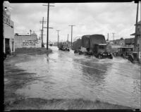Trucks driving down flooded street, Compton [1927?]
