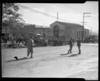 Men and trucks gathered on a muddy commercial street after a devastating flood, La Crescenta-Montrose, 1934
