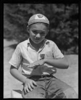 Jack Royer seated outside with a baby quail resting on his hand, Fullerton, 1935