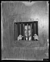 Actor Harry Moñt posing behind cell door, Los Angeles, 1935