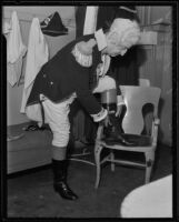 Oscar Lawler, attorney, putting on boots to complete his George Washington costume for the Los Angeles Bar Association’s historical pageant, Los Angeles, 1935