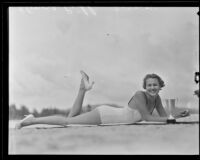 Elinore Pihl lies on a beach with a trophy, 1935