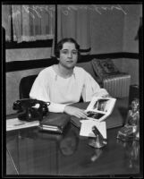 Rehba Crawford flipping through photobook at her desk, Los Angeles, 1935