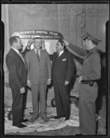 Sheriff's Pistol Team members George S. Barton, Eugene W. Biscailuz, and Sewell F. Griggers taking a shot at Kiwanis President John F. Eastwood's hat at Kiwanis Club luncheon, 1935