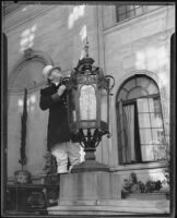Jack Jordan, doorman at the Biltmore Hotel raising a white flag to ward off pigeons, Los Angeles, 1935