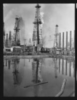 More than a dozen active oil wells dot the landscape of an oil field, Santa Fe Springs (?), 1935