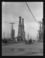 Oil well fire and nearby road with workmen and police (?), Santa Fe Springs, 1935