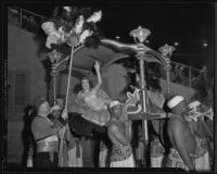 Woman waves from palanquin at shrine pageant, Los Angeles Memorial Coliseum, 1935