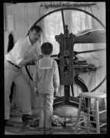 Arthur Millier operating a rolling press as a his son, Arthur, watches, Santa Monica, 1930