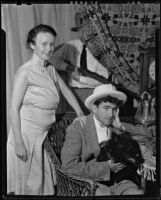 Will Harrison and his wife Evelyn Harrison (probably) in a comic pose with another man behind the curtain holding a rifle, Santa Fe (probably), 1930-1948