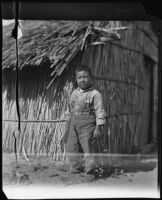 Luiseño Indian boy in front of a traditional hut (in the vicinity of the of Rancho Guajome Adobe?), 1897