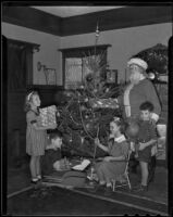 Children receive Christmas gifts from Santa at the Native Daughters of the Golden West holiday party, Los Angeles, 1935