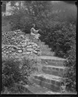 Woman tends shrubs on the slope of a large private garden, Los Angeles, 1936