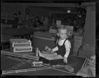Young boy plays with model train set at Toyland, Los Angeles, 1938